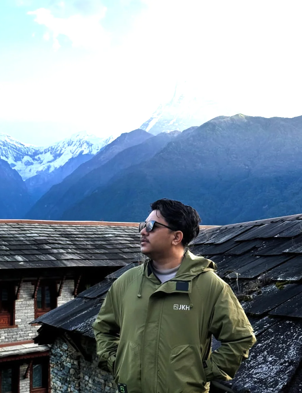 Suyog in a green jacket with mountains in the background